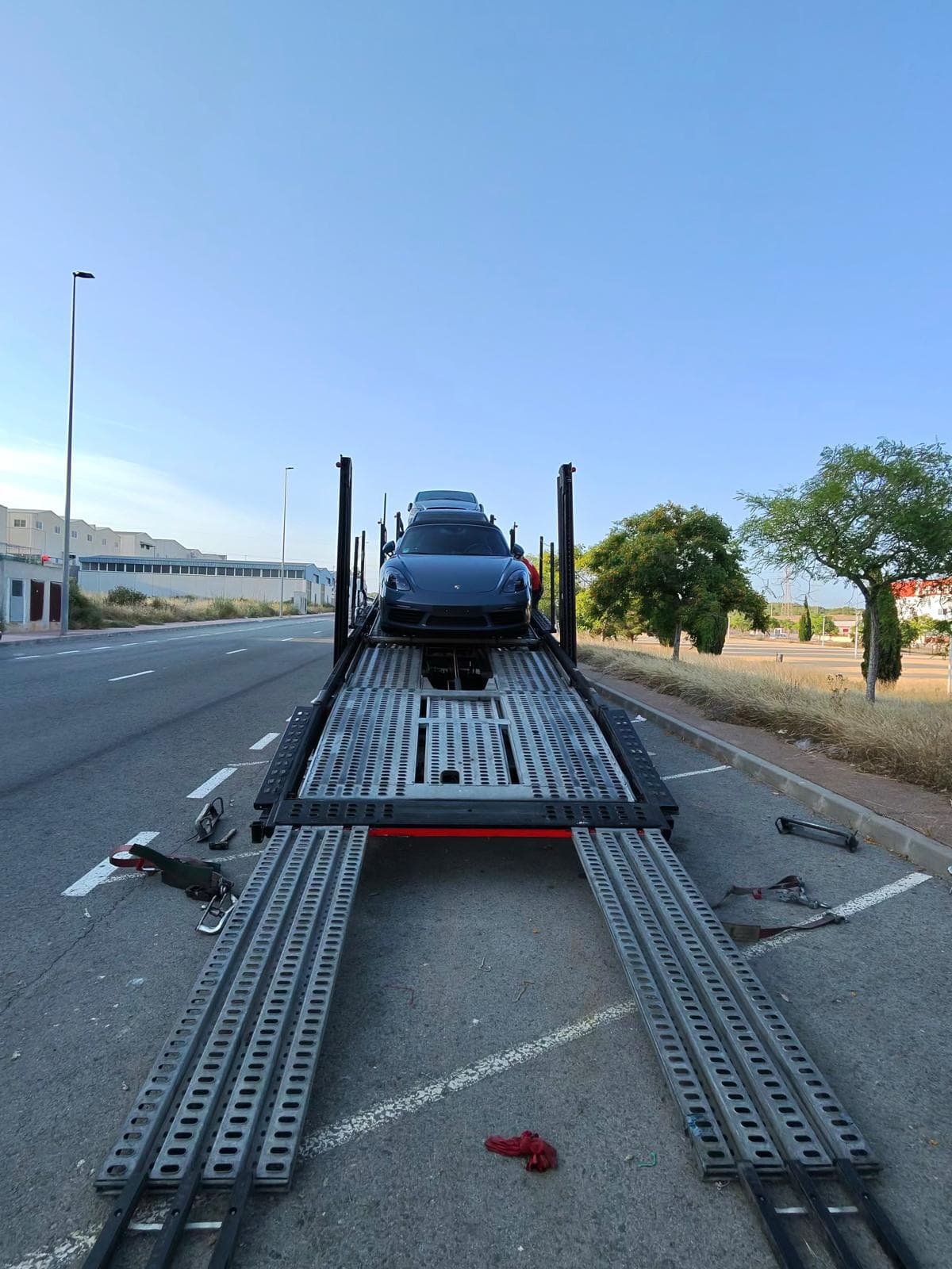 Porsche situado frente a las rampas desplegadas de un portacoches